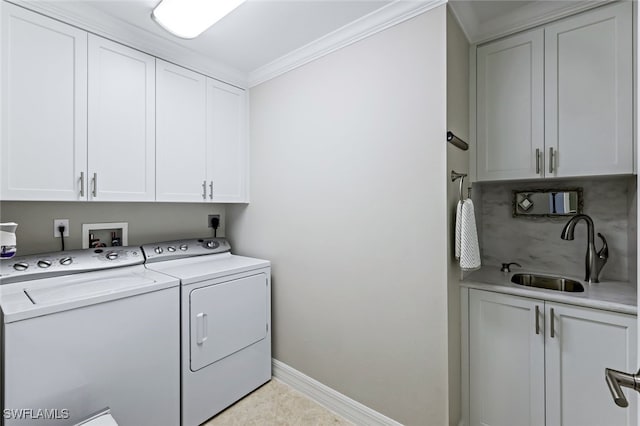 washroom with a sink, washer and dryer, cabinet space, crown molding, and baseboards