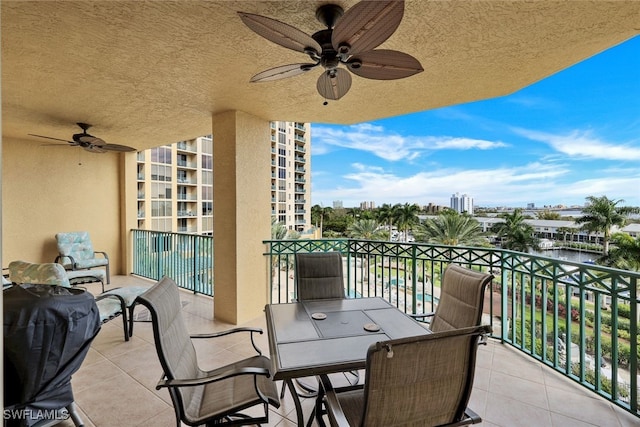 balcony featuring a city view, outdoor dining space, and a ceiling fan