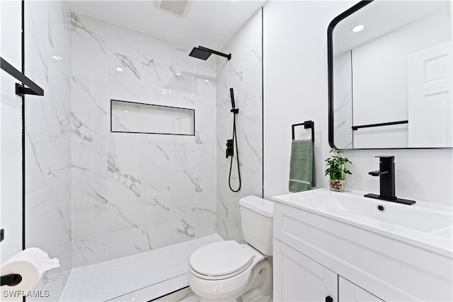 bathroom featuring toilet, vanity, and tiled shower