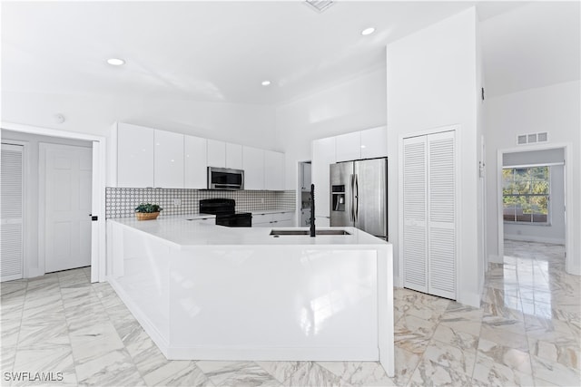 kitchen featuring white cabinets, kitchen peninsula, sink, high vaulted ceiling, and appliances with stainless steel finishes