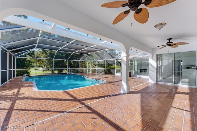 view of pool with glass enclosure, a patio, and ceiling fan