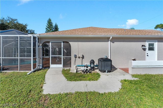 rear view of property with a patio, a lawn, and glass enclosure