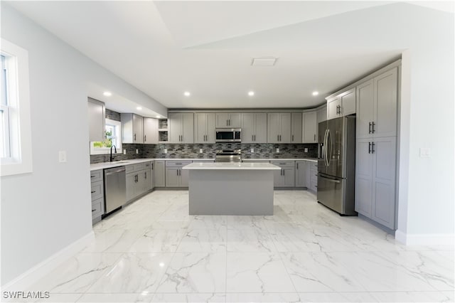 kitchen with sink, stainless steel appliances, lofted ceiling, gray cabinets, and a center island with sink