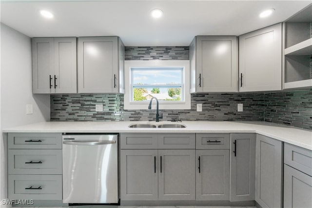 kitchen featuring gray cabinetry, decorative backsplash, dishwasher, and sink