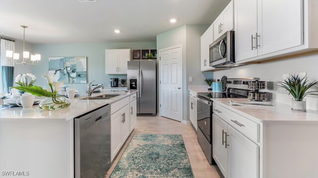 kitchen featuring sink, light hardwood / wood-style floors, stainless steel appliances, white cabinets, and a notable chandelier