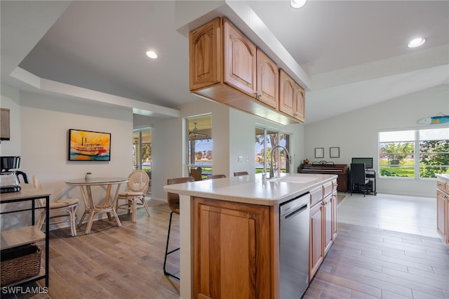 kitchen featuring lofted ceiling, sink, a center island with sink, and light wood-type flooring