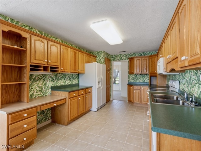 kitchen with built in desk, sink, a textured ceiling, and white appliances