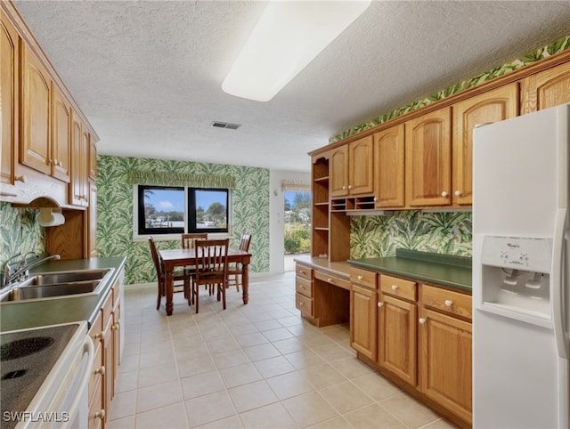 kitchen featuring white appliances, light tile patterned flooring, sink, built in desk, and a textured ceiling