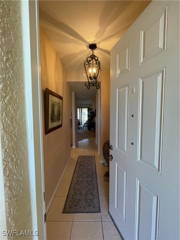 hallway with an inviting chandelier and light tile patterned floors