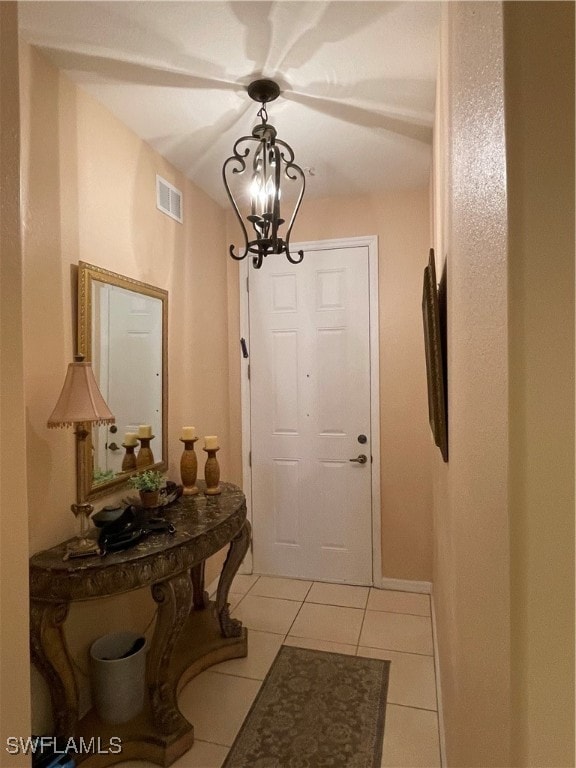 doorway to outside with a chandelier and light tile patterned floors