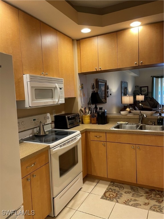 kitchen with white appliances, light tile patterned floors, and sink