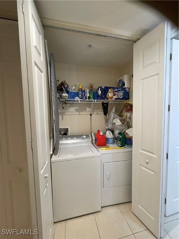 clothes washing area with independent washer and dryer and light tile patterned floors