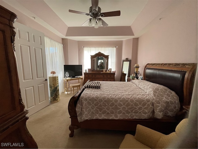 bedroom with ceiling fan, a raised ceiling, and carpet