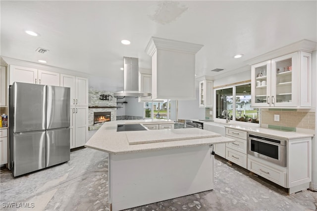 kitchen featuring backsplash, kitchen peninsula, stainless steel appliances, wall chimney exhaust hood, and white cabinets