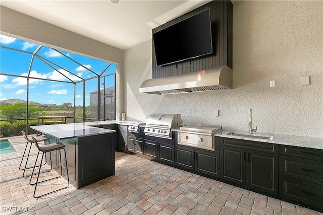 view of patio / terrace with glass enclosure, area for grilling, a mountain view, and a wet bar