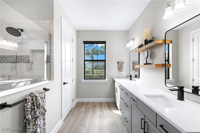 bathroom with tiled shower, vanity, and hardwood / wood-style flooring