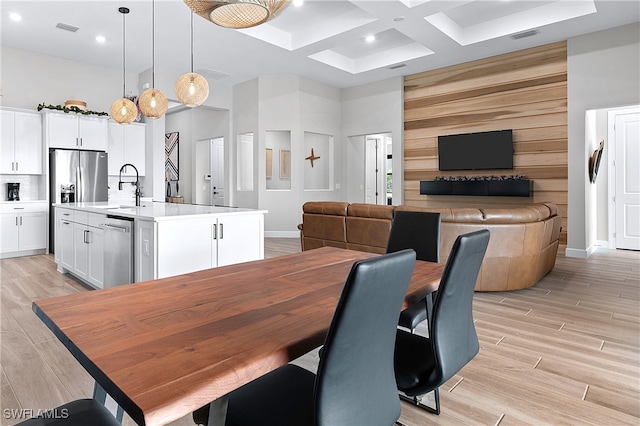 dining space featuring sink, beamed ceiling, a high ceiling, and coffered ceiling