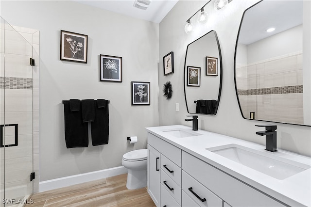 bathroom with hardwood / wood-style floors, vanity, toilet, and an enclosed shower