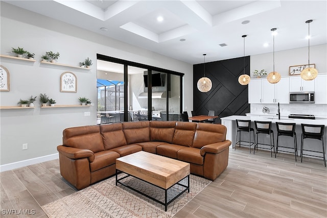 living room featuring beamed ceiling, coffered ceiling, and sink