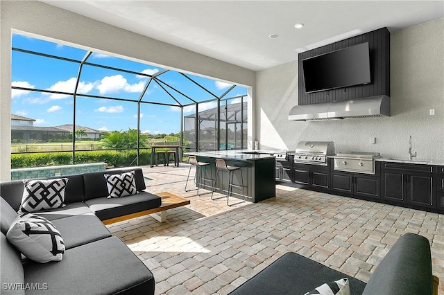 view of patio with outdoor lounge area, glass enclosure, an outdoor kitchen, area for grilling, and a wet bar