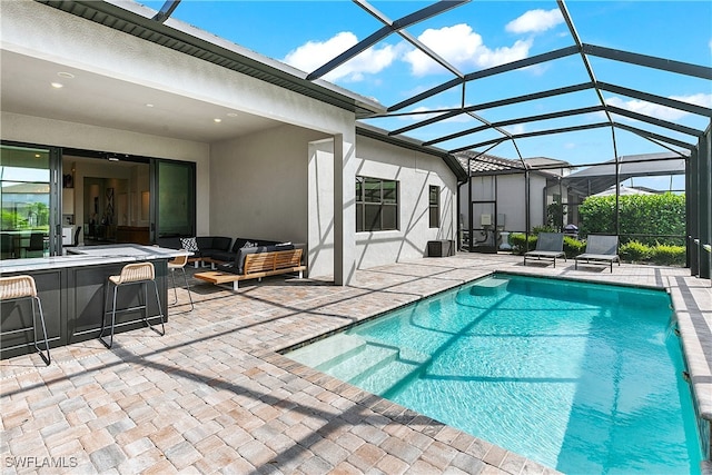 view of pool featuring glass enclosure, an outdoor living space, pool water feature, a bar, and a patio