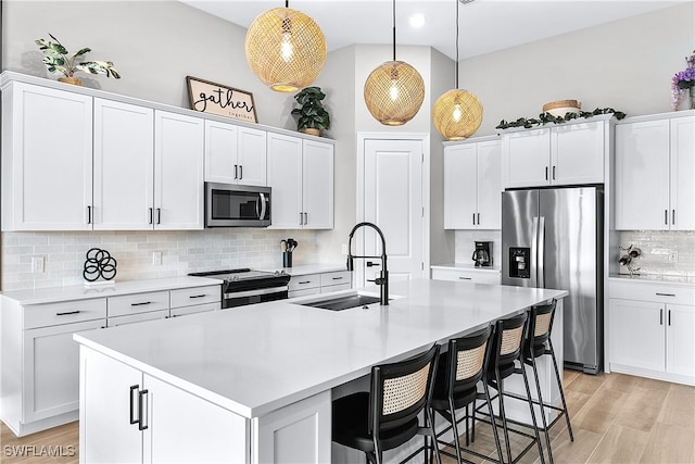 kitchen featuring a center island with sink, white cabinets, pendant lighting, and appliances with stainless steel finishes