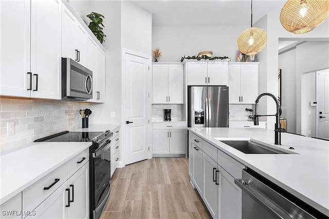 kitchen featuring white cabinetry, decorative light fixtures, and appliances with stainless steel finishes