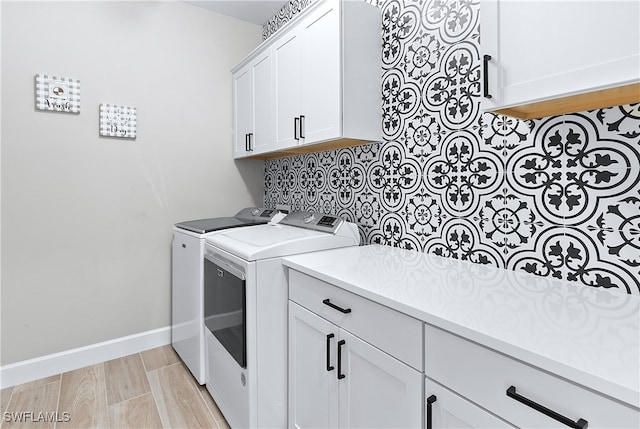 laundry area featuring cabinets, independent washer and dryer, and light hardwood / wood-style flooring