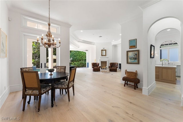 dining space featuring light hardwood / wood-style floors, an inviting chandelier, ornamental molding, and sink