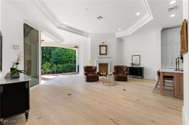 sitting room featuring crown molding, a tray ceiling, and light hardwood / wood-style flooring