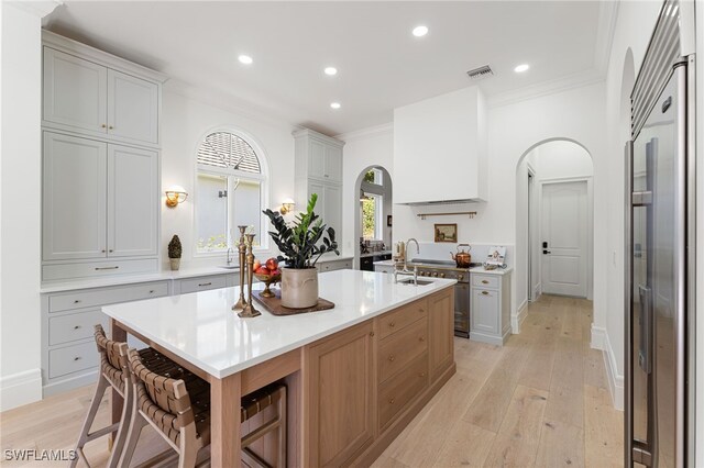 kitchen featuring ornamental molding, light hardwood / wood-style flooring, high end fridge, and a healthy amount of sunlight