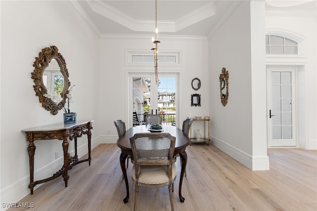 dining room featuring a tray ceiling, light hardwood / wood-style flooring, french doors, and ornamental molding