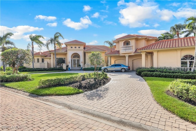 mediterranean / spanish home featuring a balcony, a garage, and a front lawn