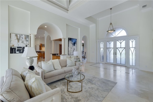 living room with ornate columns, a towering ceiling, crown molding, and french doors