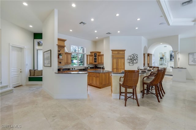 kitchen featuring kitchen peninsula, a kitchen island, a breakfast bar area, and dark stone countertops