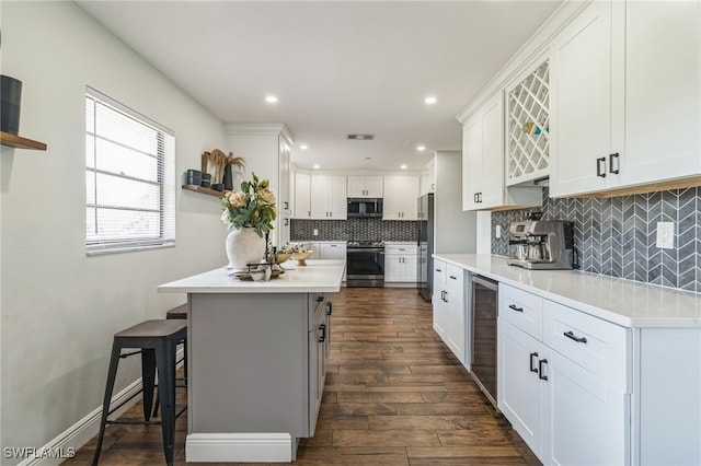 kitchen featuring dark hardwood / wood-style floors, a kitchen breakfast bar, a center island, white cabinets, and appliances with stainless steel finishes