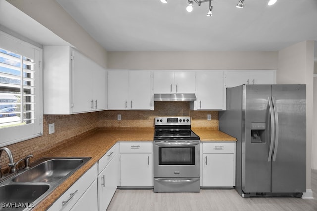 kitchen featuring decorative backsplash, appliances with stainless steel finishes, white cabinetry, light wood-type flooring, and sink