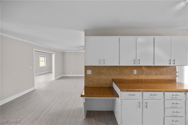 kitchen featuring crown molding, light hardwood / wood-style flooring, and white cabinets