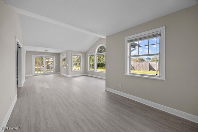 unfurnished living room featuring french doors, wood-type flooring, and vaulted ceiling with beams