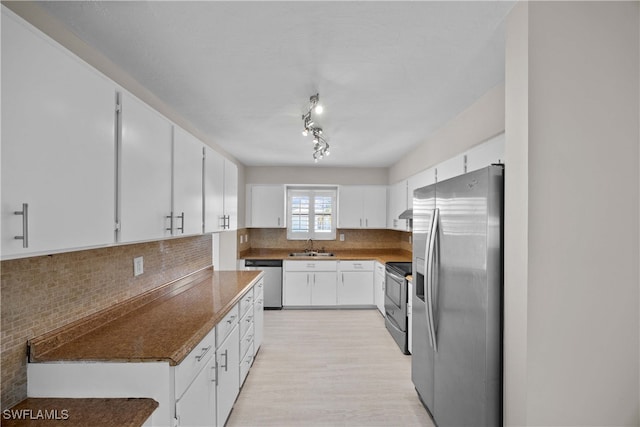 kitchen featuring backsplash, sink, light wood-type flooring, white cabinetry, and appliances with stainless steel finishes