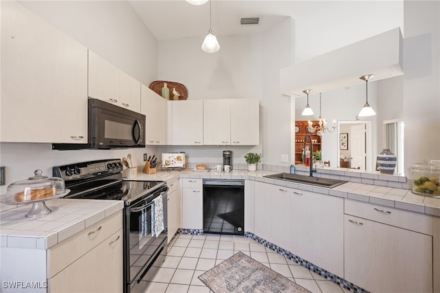 kitchen featuring sink, black appliances, decorative light fixtures, and a high ceiling