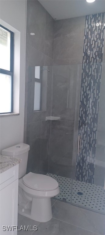 bathroom featuring vanity, tile patterned flooring, toilet, and an enclosed shower