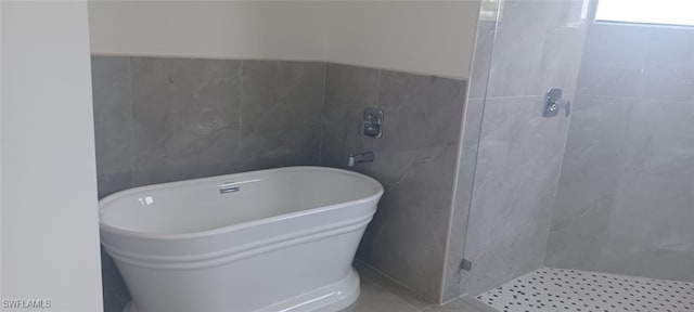 bathroom featuring tile walls and separate shower and tub