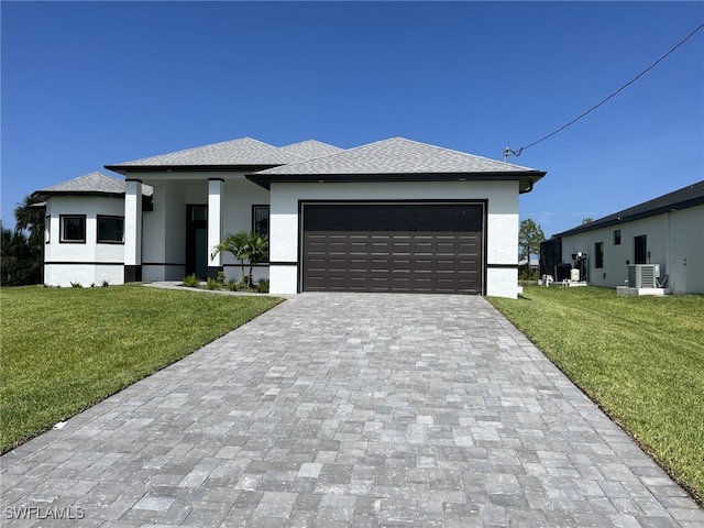 view of front of home featuring a garage, a front lawn, and central air condition unit