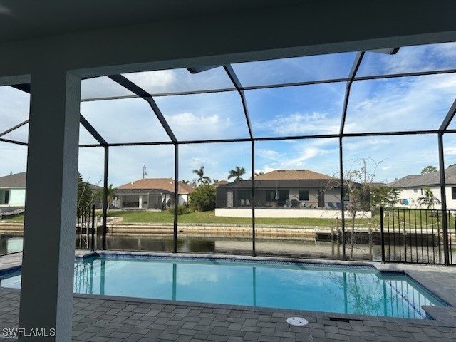 view of pool featuring a patio, a water view, and a lanai