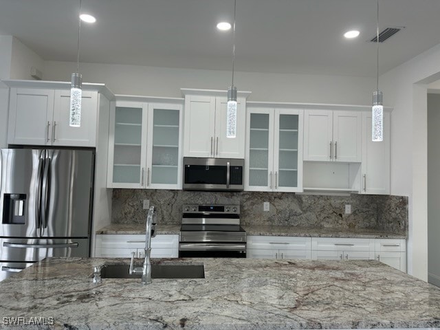 kitchen featuring stainless steel appliances, sink, pendant lighting, and white cabinets