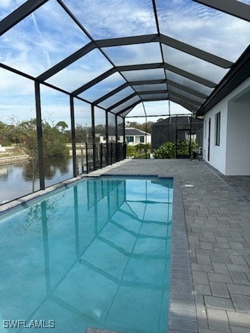 view of swimming pool with a patio, a lanai, and a water view