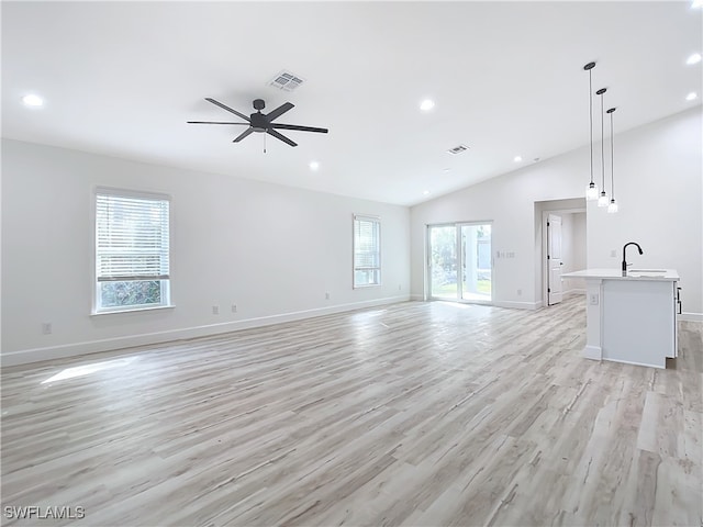 unfurnished living room featuring ceiling fan, light wood-type flooring, sink, and vaulted ceiling