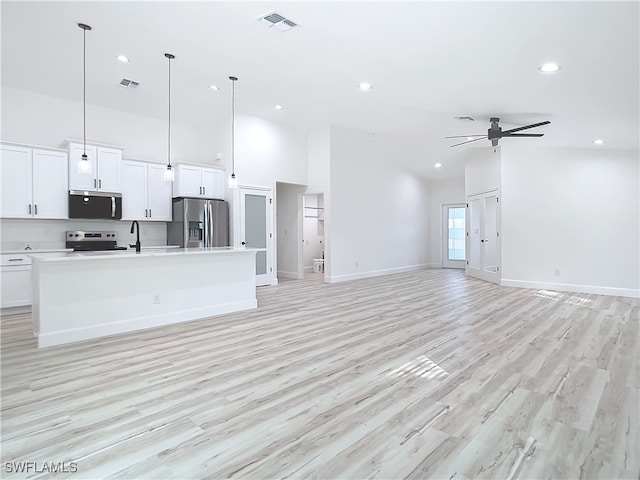 unfurnished living room with a towering ceiling, light hardwood / wood-style floors, ceiling fan, and sink