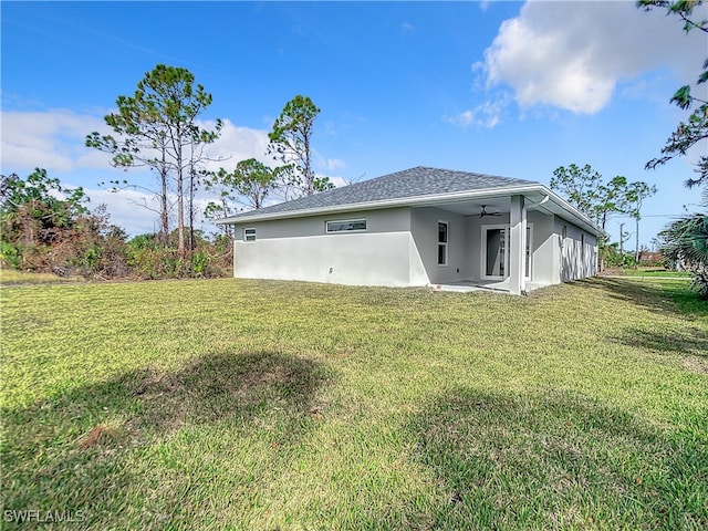 back of property with ceiling fan and a yard